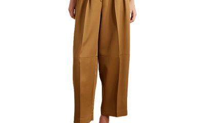 A woman wearing brown tailored pants, black heels, and a light brown top