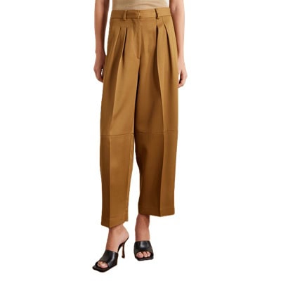 A woman wearing brown tailored pants, black heels, and a light brown top