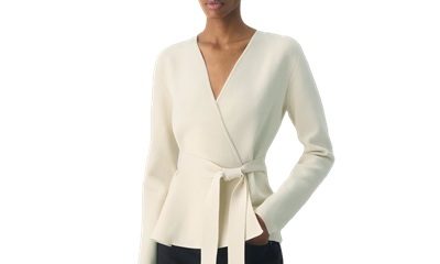 A woman wearing a cream colored cardigan and black pants