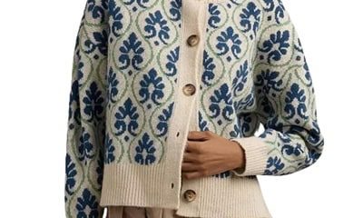 A woman wearing a light brown skirt with a blue, green, and ivory floral cardigan