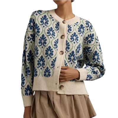 A woman wearing a light brown skirt with a blue, green, and ivory floral cardigan