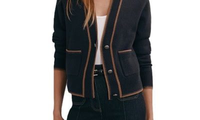 A woman wearing black pants, black belt, white top, and navy pocket cardigan with brown trim