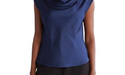 A woman wearing black pants and a navy sleeveless cowl-neck top
