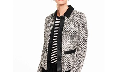 A woman wearing black pants, a black-and-white striped top, and ivory/black tweed jacket with black trim