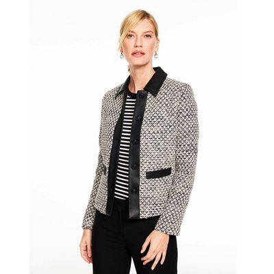 A woman wearing black pants, a black-and-white striped top, and ivory/black tweed jacket with black trim