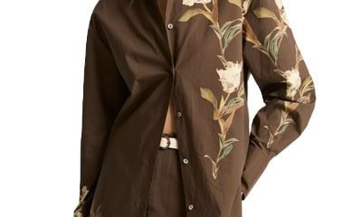 A woman wearing a brown floral button-front blouse and brown skirt