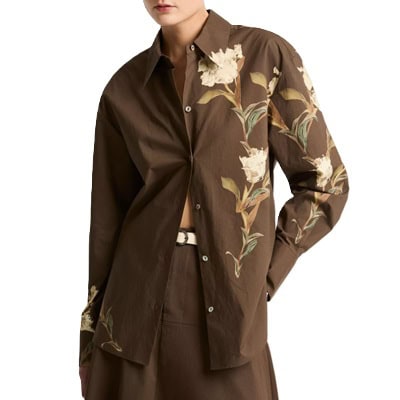 A woman wearing a brown floral button-front blouse and brown skirt