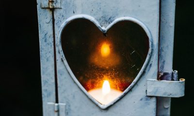 a candle burns behind a heart-shaped cutout
