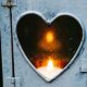 a candle burns behind a heart-shaped cutout