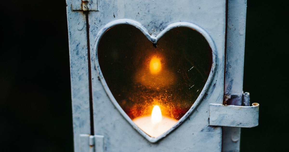 a candle burns behind a heart-shaped cutout