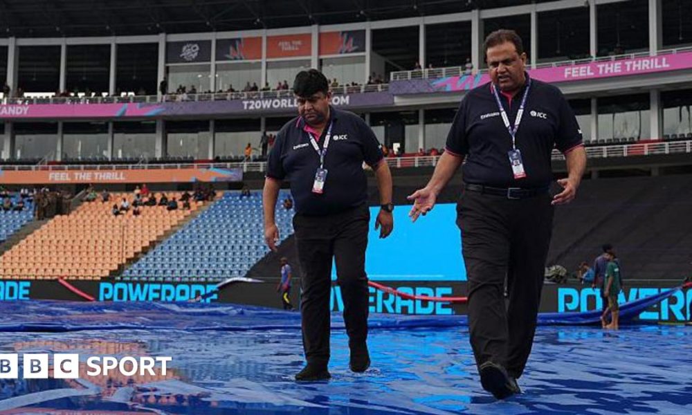 ICC officials walk on rain-soaked covers at  Pallekele Cricket Stadium in Kandy