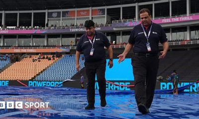 ICC officials walk on rain-soaked covers at  Pallekele Cricket Stadium in Kandy
