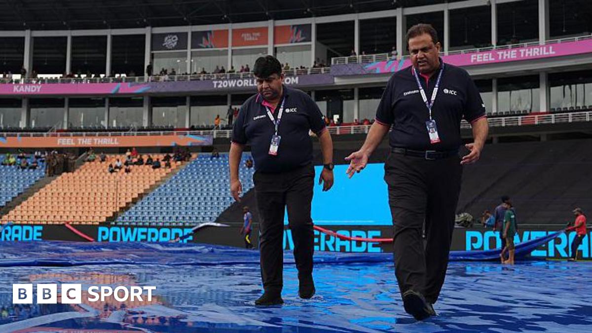 ICC officials walk on rain-soaked covers at  Pallekele Cricket Stadium in Kandy