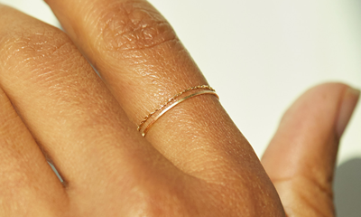 woman wears two rings, stacked together -- the rings look more like necklace chains than regular rings