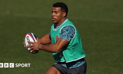 Immanuel Feyi-Waboso running with the ball during an England training camp. He has short black hair and is wearing a green bib with a blue training top and shorts.