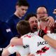 Canadian curlers celebrate after their defeat of Great Britain's team, two members of which are seen on the right