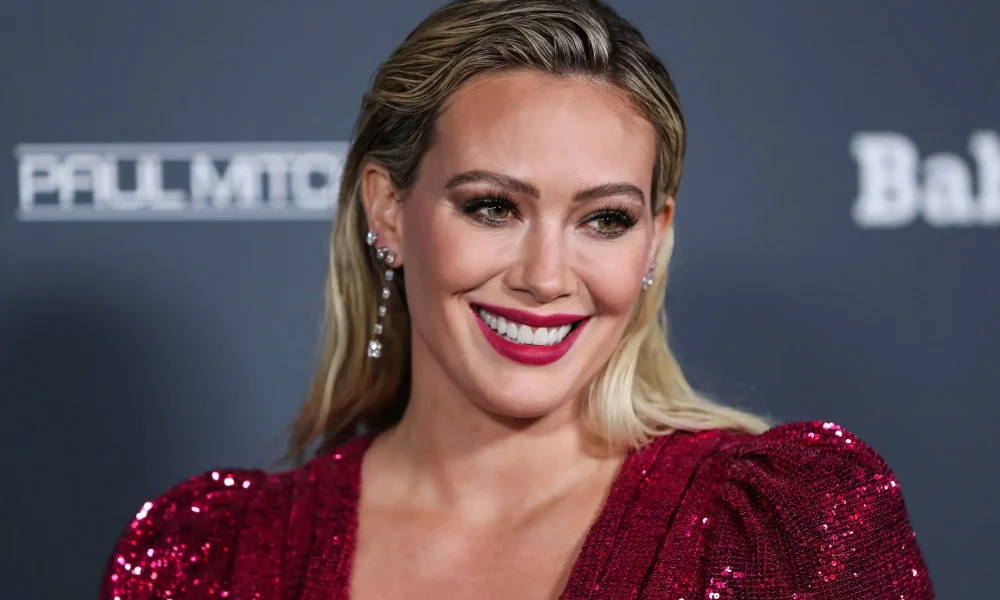 Hilary Duff wearing an Osman dress and Rahamoniv jewelry while wearing shoes and carrying a clutch by Jimmy Choo arrives at the Baby2Baby 10-Year Gala 2021