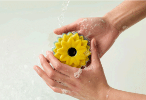 A pair of hands holding a sunflower shaped bar of soap