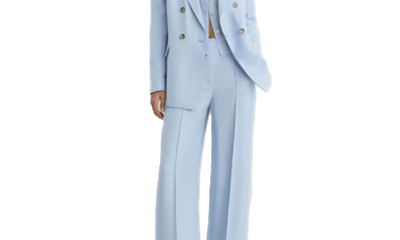woman wears double-breasted light blue suit with wide legs; her blouse has the top few buttons buttoned but gapes open at the waist (?)