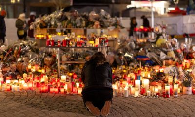 A woman lights a candle at a memorial outside the Le Constellation bar. Pic: Reuters