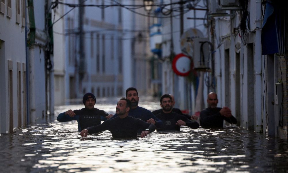 Volunteers wade through a flooded street in Alcacer do Sal. Pic: Reuters