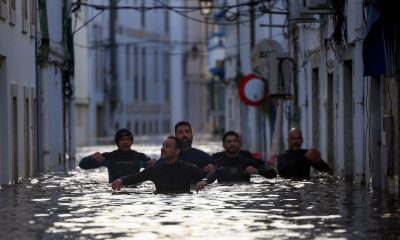 Volunteers wade through a flooded street in Alcacer do Sal. Pic: Reuters