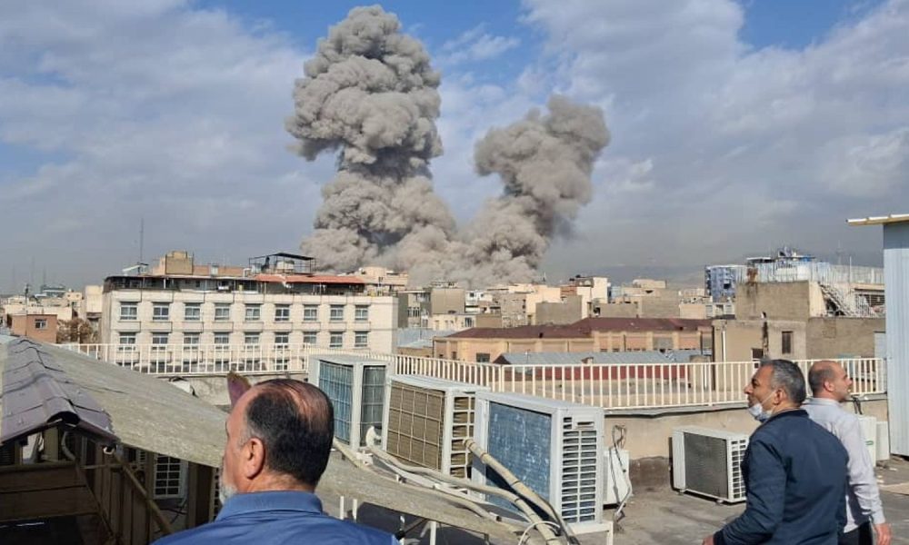 People watch as smoke rises after an explosion in Tehran. Pic: AP