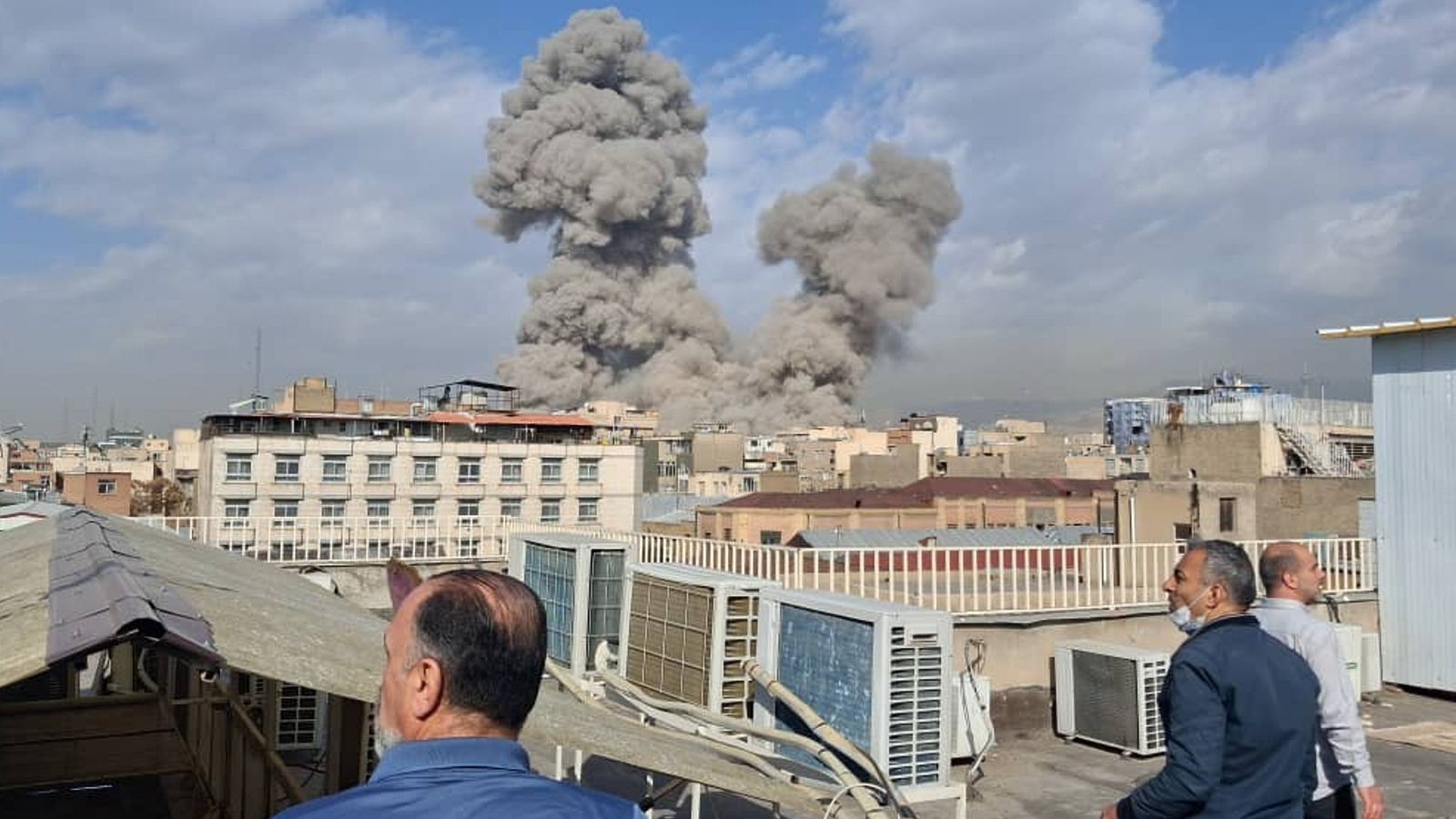 People watch as smoke rises after an explosion in Tehran. Pic: AP