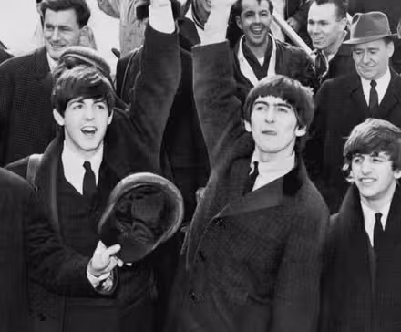 Surrounded by press, The Beatles wave at fans as they arrive in New York City in 1964.