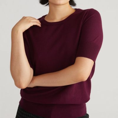 A woman wearing a short-sleeve purple sweater and matching pants