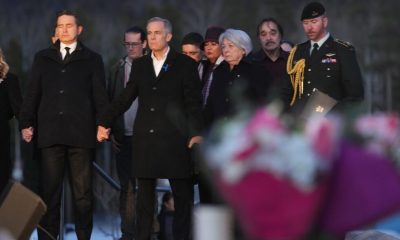 Prime Minister Carney and Canada's main opposition leader hold hands during school shooting vigil