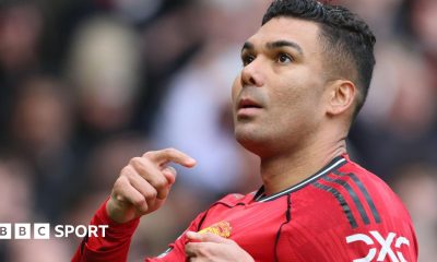 Manchester United midfielder Casemiro points to the club badge on his red shirt