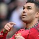 Manchester United midfielder Casemiro points to the club badge on his red shirt