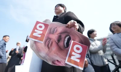 A man holds a picture of U.S. President Donald Trump after a news conference against Trump's demands to multiple countries to send warships to keep the Strait of Hormuz open, near the U.S. Embassy in Seoul, South Korea, on March 16.