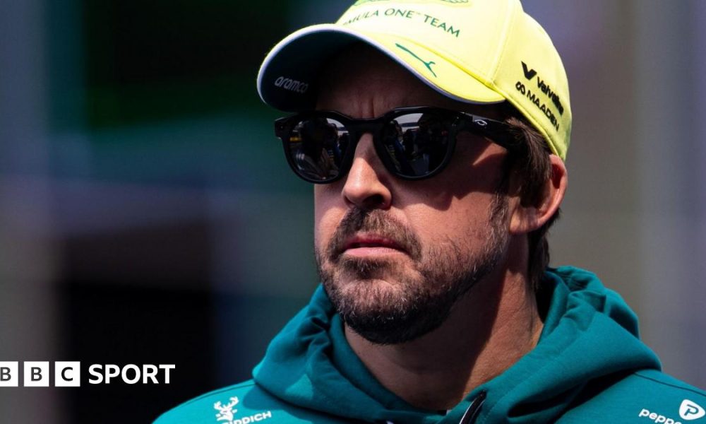 Fernando Alonso wearing sunglasses, an Aston Martin hoodie and a yellow cap