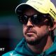 Fernando Alonso wearing sunglasses, an Aston Martin hoodie and a yellow cap