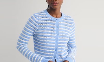 A woman wearing a blue-and-white striped cardigan and dark blue jeans