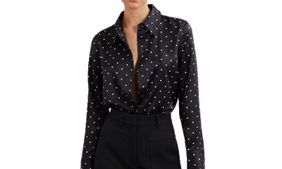 A woman wearing black pants and a black-and-white polka-dot blouse