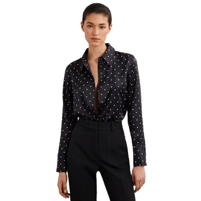 A woman wearing black pants and a black-and-white polka-dot blouse