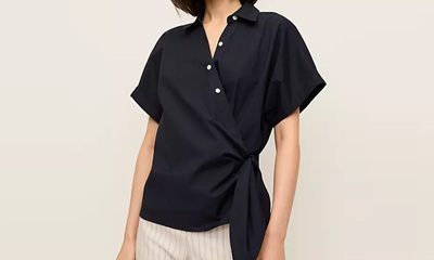 A woman wearing a black tie-waist top and striped ivory pants