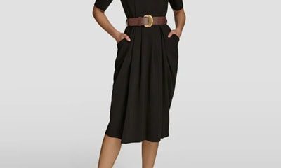 A woman wearing a black dress with brown belt and brown heels