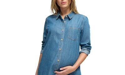 A pregnant woman wearing a blue denim button-front shirt and darker blue jeans