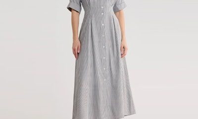 A woman wearing a black-and-white striped midi shirtdress and white sandals