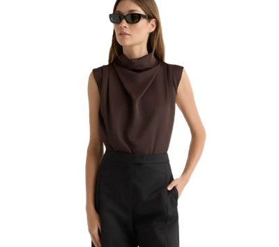 A woman wearing black pants, brown sleeveless top, and black sunglasses