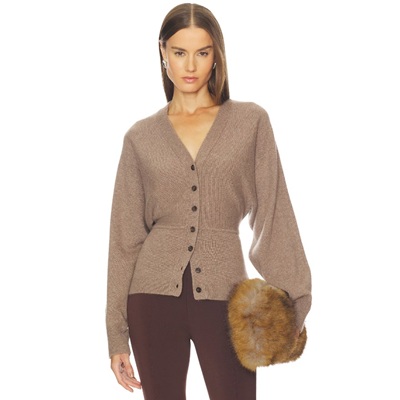 A woman wearing a light brown cardigan, dark brown pants, and holding a fur clutch