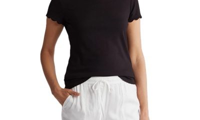 A woman wearing a black scalloped tee and white drawstring pants