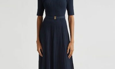 A woman wearing a belted navy ribbed midi dress and brown sandals