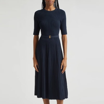 A woman wearing a belted navy ribbed midi dress and brown sandals