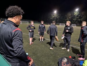 A group of four of the Great Western FC team getting ready to play a game on an outdoor pitch at night time