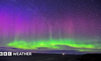 The northern lights shining bright in the night sky with bright green colours in the lower part of the sky and purples higher up